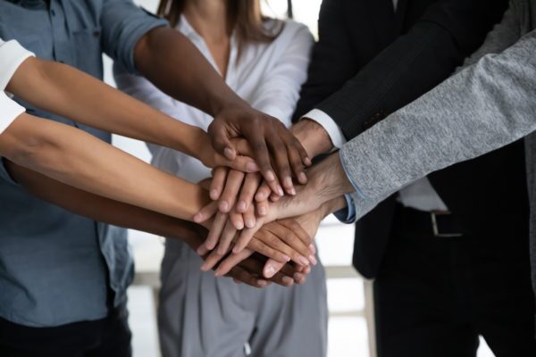 Close up diverse colleagues stacking hands, showing unity and support Team Building at Prototype Escape Games